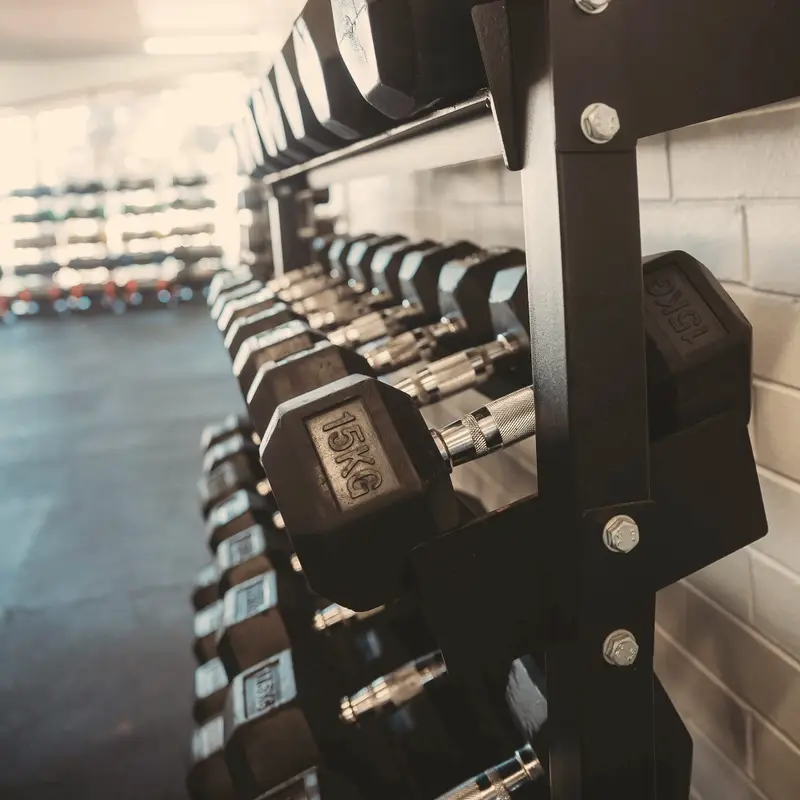 Close-up of a rack of black hexagonal dumbbells, with the nearest pair in sharp focus.