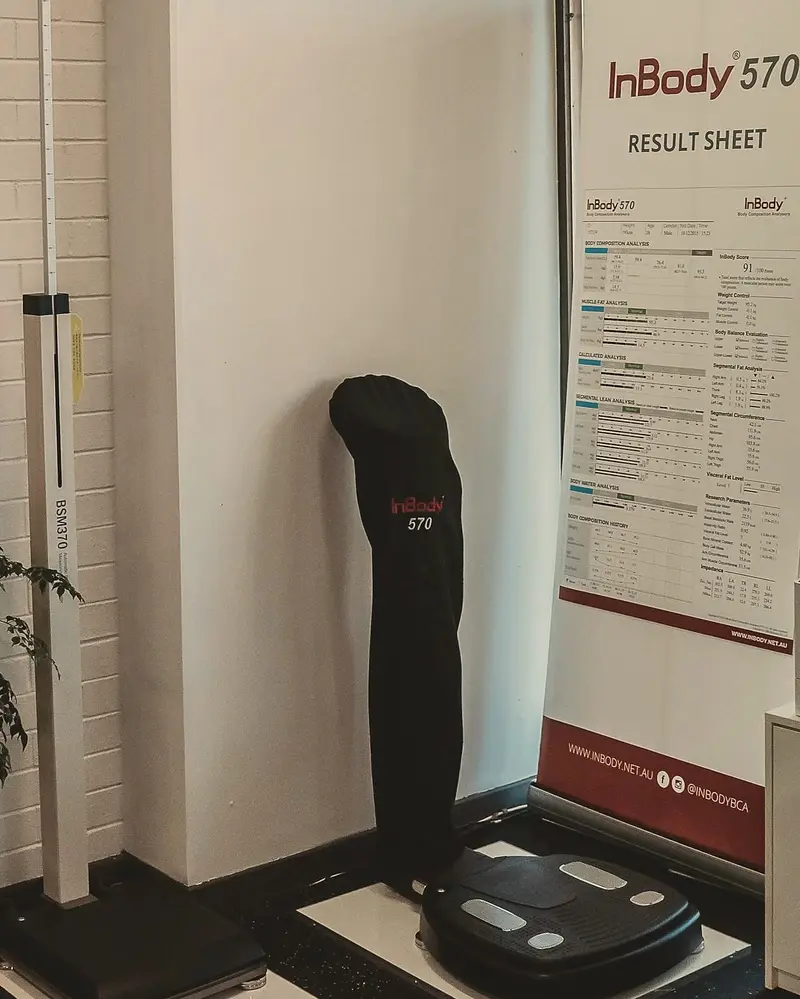 The InBody 570 body composition scanner under its black cover, beside a banner showing an InBody result sheet.